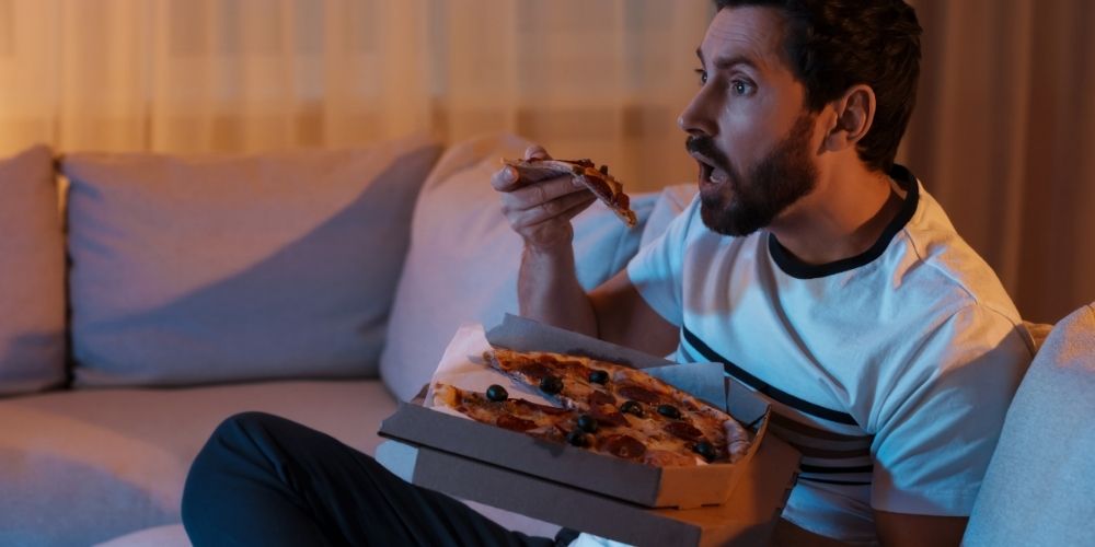 Man-Eating-Pizza-Watching-TV-Sofa-Night_1.jpg
